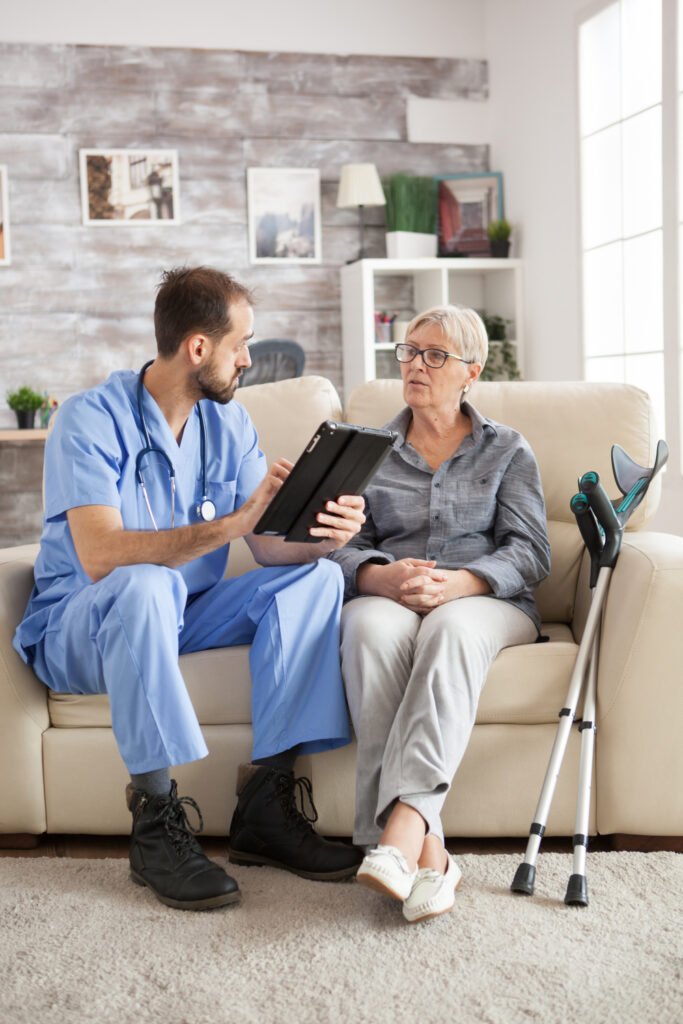 Old woman with crutches in nursing home sitting on couch